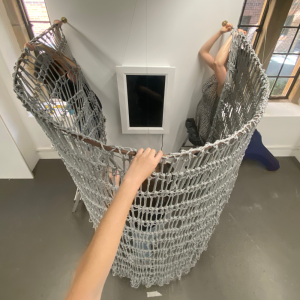 Redirecting gaze -- A creative feminist practice redefining the visual relationship between viewer and subject, aimed at shifting power and restoring agency, 2024, recycled cotton rope, digital monitor, digital silver gelatin image, copper, brass, gilded timber, upcycled carpet and digital sensors